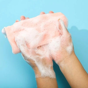 Close-up of pink 6-layer foaming net producing rich white lather between hands