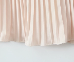 Detail of the pleated hem on an elegant pale pink dress with high-quality edge stitching