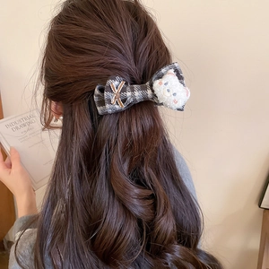 Detail showing checkered bow hair clip with plush bear on wavy long hair