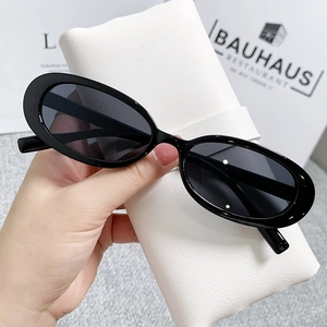 Retro black oval sunglasses with dark lenses and a white lychee leather storage bag