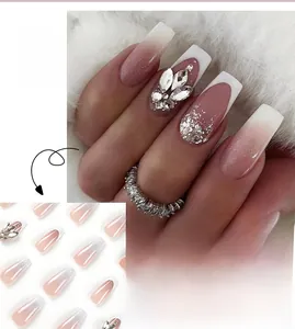 Macro detail of French tip press-on nails with pink gradient and rhinestone accents