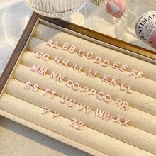 Lettere dell'alfabeto in resina rosa A-Z su un vassoio beige per creazioni di gioielli