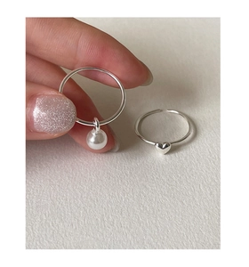 Detail of 925 sterling silver rings with elegant pearl pendant and small heart charm