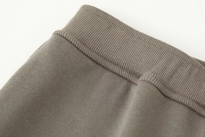 Detailed close-up of taupe knit fabric with ribbed cuffs and double stitching quality