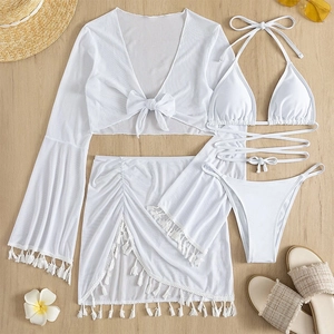 Flat lay of white four-piece fringe bikini set with mesh cover-up on wooden floor