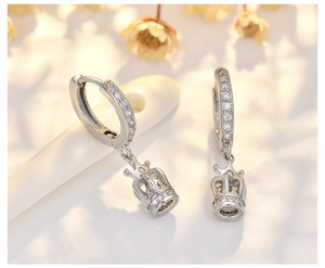 Macro shot of silver crown drop earrings with sparkling cubic zirconia on a warm background