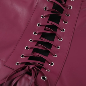 Détail de robe en cuir bordeaux avec laçage corset et œillets métalliques