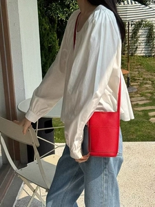Red lychee grain leather crossbody phone bag shown on shoulder in outdoor cafe
