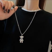 Detail of silver snake chain necklace featuring a white bear pendant on black clothing