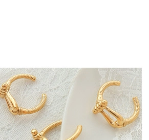 Close-up of 18K gold-plated C-shaped earrings with equestrian buckle and ribbed texture