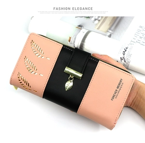 Detail of pink and black bi-fold leather wallet with hollow leaf design and metal pendant