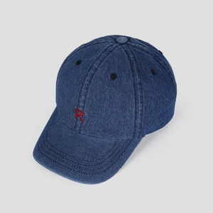 Detail of red embroidered R letter on dark blue denim baseball cap with reinforced stitching