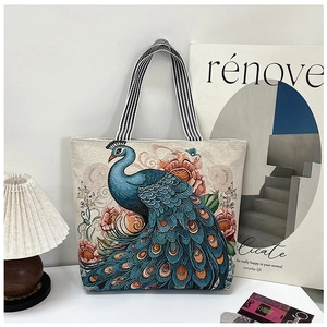 Close-up of vibrant peacock embroidery and floral patterns on a canvas tote bag detail