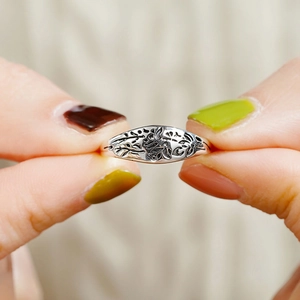Macro detail of a vintage silver rose relief ring showing fine floral embossed textures