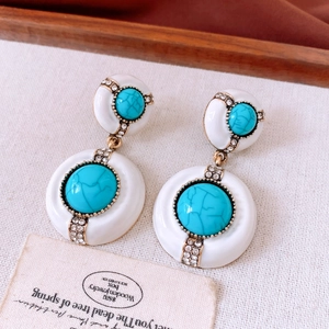 Détail de boucles d'oreilles vintage rondes avec pierre turquoise et accents de diamants