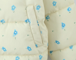 Detail of floral hooded puffer jacket featuring blue flower print and a side pocket