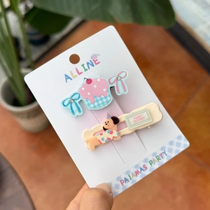 Detail of pink cake and yellow puppy acrylic hair clips on a white display card