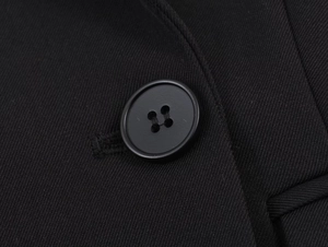 Close-up of a matte black four-hole resin button on a black twill blazer jacket