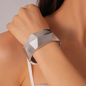 Macro view of silver geometric cuff bracelet showing radial faceted texture and metallic finish