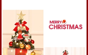 Close-up of a lit mini Christmas tree with red bows, gold bells, and festive ornaments