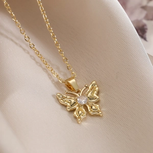Elegant gold plated butterfly pendant necklace with zircon stone on silk fabric background