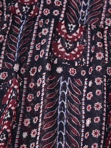 Close-up of lightweight navy blue fabric with red paisley pattern and sheer texture