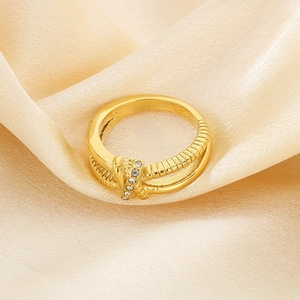 Macro detail of gold knot ring with rhinestones on champagne silk background