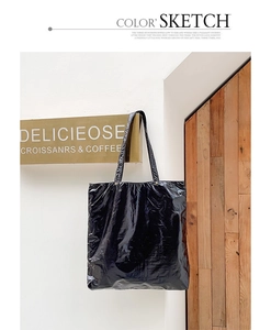 Detail of black tote bag with unique crinkled glossy texture and dual thin straps