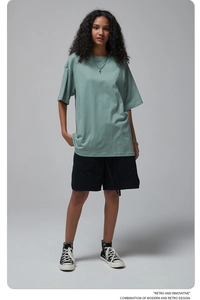 Detail of a pea green oversize cotton t-shirt with drop shoulders on a studio model