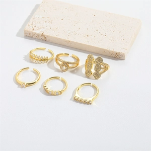 Detail of six adjustable gold rings with zircon and leaf motifs on a stone display