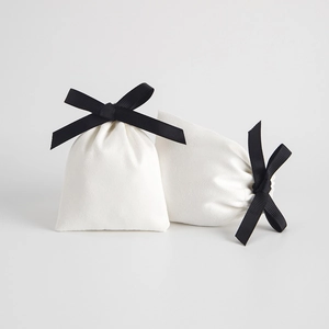 White microfiber jewelry pouches with black drawstring bows for elegant packaging
