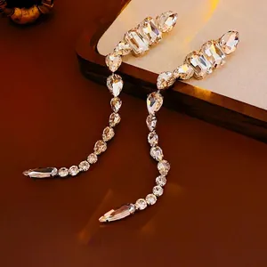 Sparkling crystal tassel earrings with teardrop and rectangular stones on wooden display