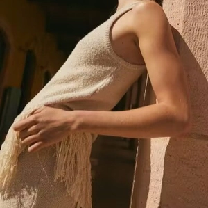 Top in maglia senza maniche beige con orlo a frange e trama di maglia testurizzata
