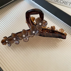 Détail macro d'une pince à cheveux fleur en résine ambre avec cristal et plateau mat