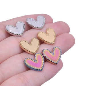 Close-up of heart-shaped stainless steel charms with caviar bead borders in three colors