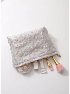Floral embossed cosmetic bag in light grey with pink flowers and makeup accessories