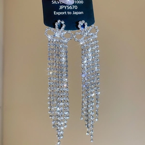 Close-up of silver tassel earrings with diamond ribbon knots and hanging water-drill chains