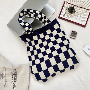 Détail du sac cabas en tricot à damier bleu et blanc avec poignées en tissu texturé