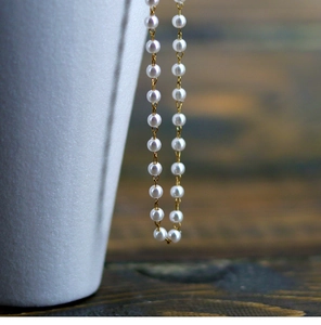 Macro shot of elegant white pearls on a fine gold chain with high-quality beads texture