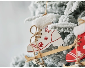 Close-up of white wooden ice skate ornament with red snowflakes and rustic twine bells