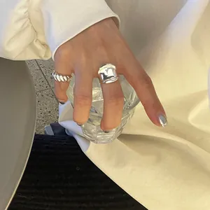 Close-up of minimalist 925 sterling silver twist and wide concave rings on a hand