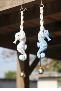 Outdoor close-up of wooden seahorse wind chime with cotton rope and golden bell
