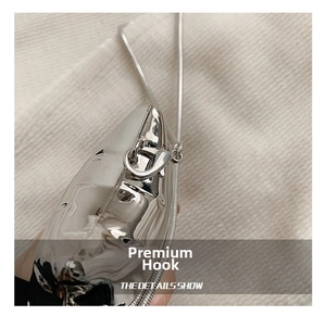 Detail of silver mirror metal charm with artistic texture and lobster clasp for evening bag