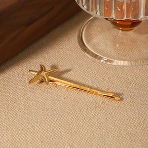 Pince à cheveux étoile de mer dorée pour femme sur fond de tissu texturé