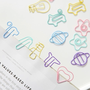Colorful creative shaped metal paperclips including animal and star patterns on book pages
