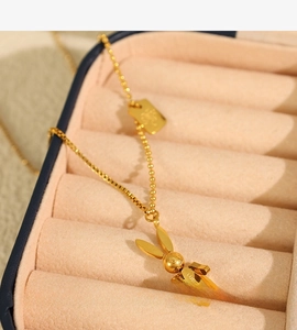 Detailed close-up of golden robot rabbit pendant with Luck engraving on a beaded chain