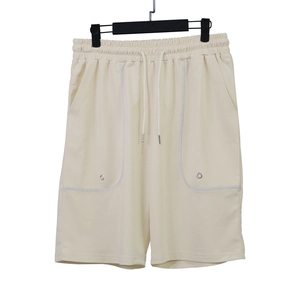 Détail d'un short de sport beige avec taille à cordon et poches à coutures blanches