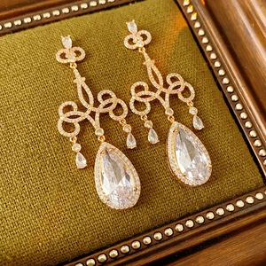 Détail macro de boucles d'oreilles en zircone poire avec filigrane doré complexe