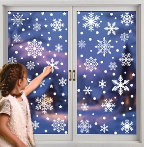 Close-up of a child applying white snowflake window stickers for cozy winter Christmas decor
