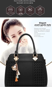 Detail of black leather handbag with lychee texture and woven pattern and petal tassel